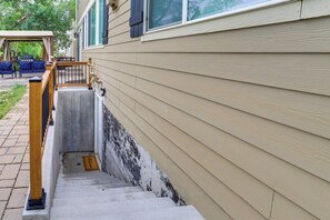 A residential exterior with a beige siding house, a concrete stairway with a metal handrail, and a covered outdoor seating area. - 5 Mi to Barr Lake! Suburban Family Retreat (Brighton)