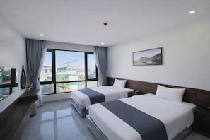 A hotel room with two beds, a large window with curtains, a flat-screen TV, and a painting on the wall. - The Sun Hotel - Ninh Bình (Ninh Binh)