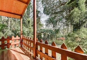 A wooden deck with a railing overlooking a lush, green forest.