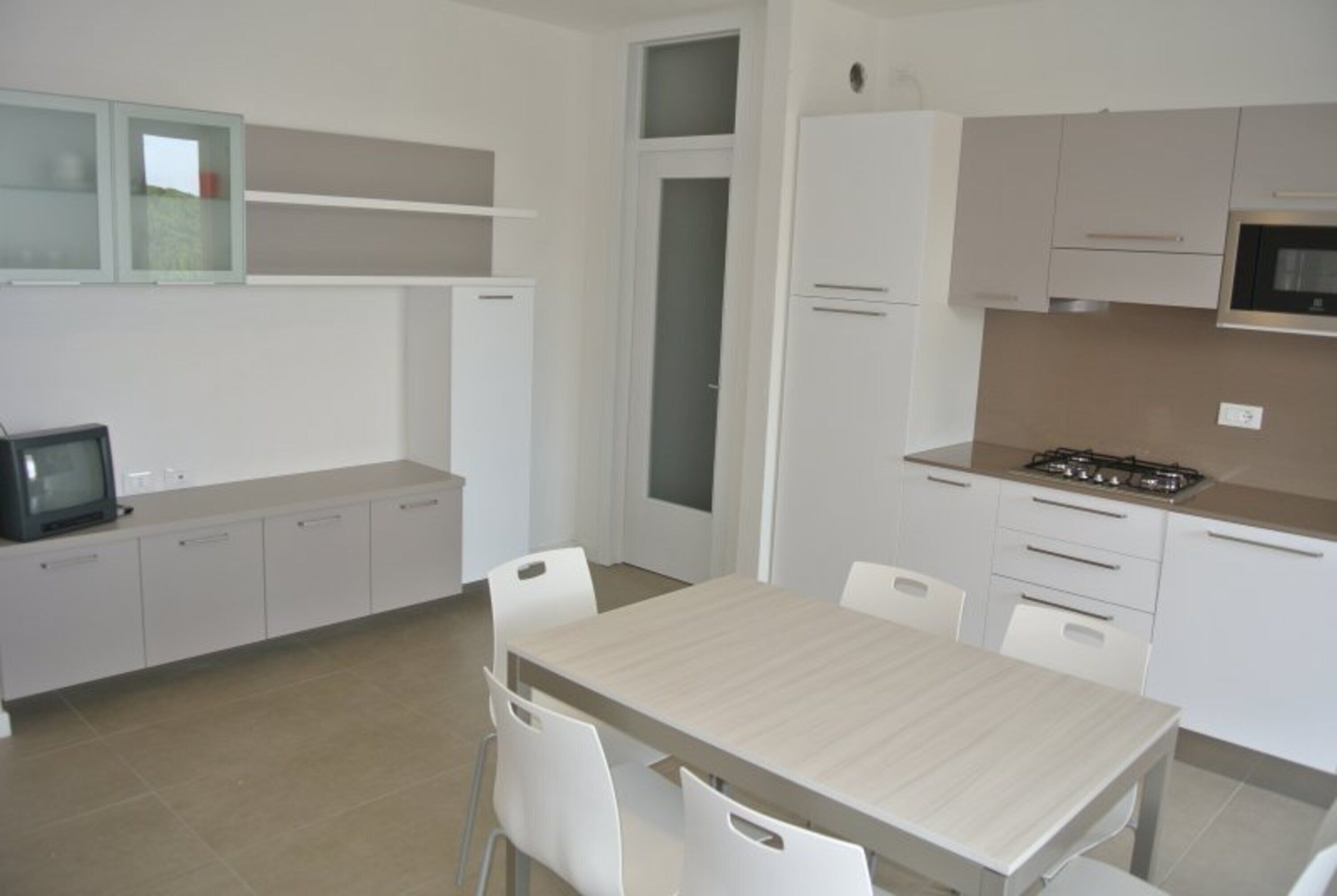 A modern kitchen with white cabinets, a dining table, and chairs.