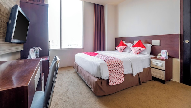 Een hotelkamer met een bed, nachtkastje en een aan de muur bevestigde televisie.
