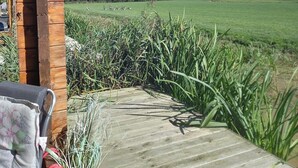 A wooden deck with a lantern, a chair, and a potted plant.