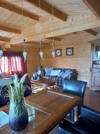 Un interno in legno con un tavolo da pranzo, sedie, un divano e lampadari di cristallo a sospensione.. Cabin Sleeps 4 With Hot Tub and Garden