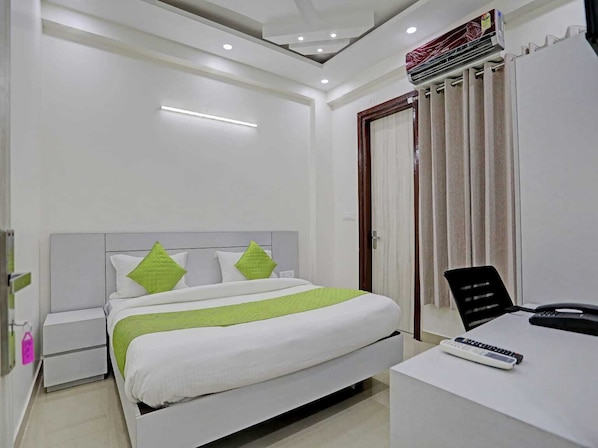Ein modernes Hotelzimmer mit Bett, Nachttischen, einem Schreibtisch mit Telefon und Fernbedienung sowie einer Klimaanlage.