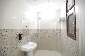 Een badkamer met een wastafel, spiegel, douche en decoratieve wandtegels.