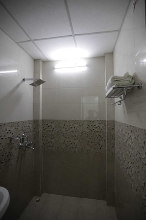 A small, tiled bathroom with a shower, a toilet, and a towel rack. - The Vertigo (Noida)