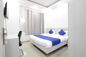 Een moderne hotelkamer met een bed, gordijnen, een televisie en een stoel.