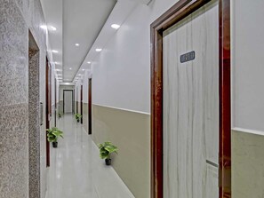 A corridor with doors, potted plants, and a sign indicating room number 101. - The Vertigo (Noida)