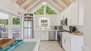 A kitchen with white cabinets, a microwave, a refrigerator, and a sink.