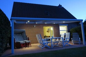 A covered patio with outdoor furniture and a brick house. - Holiday home in Norden with swimming pool (Norden)