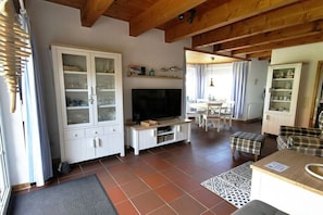Ein Wohnzimmer mit Fernseher, Schränken und Essbereich.