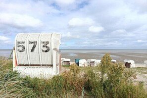 Eine Strandlage mit einer großen Hinweisschild, Strandkörben und Blick auf das Meer.