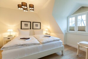 A bedroom with a bed, bedside lamps, a window with blinds, and a ceiling light fixture. - Holiday home in Hörnum with swimming pool (Hörnum)
