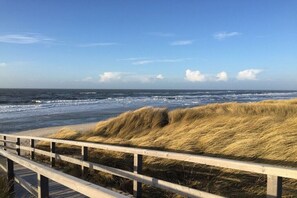 A wooden boardwalk leading to a beach with dunes and the ocean in the background. - Holiday home in Hörnum with swimming pool (Hörnum)