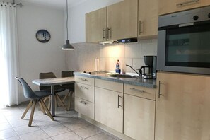 Eine moderne Küche mit Essbereich, ausgestattet mit einem runden Tisch, Stühlen, Schränken, einer Spüle und einem Backofen.