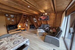 A cozy cabin interior with a wooden interior, a sofa, a television, and a staircase. - Dream in Carolinensiel (Carolinensiel)