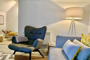 En moderne stue med en grå sofa, en blå lænestol og en gulvlampe.