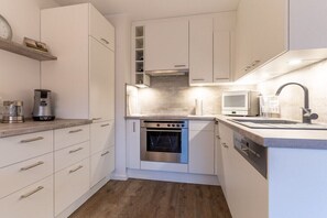 Eine moderne Küche mit weißen Schränken, einem Backofen, einer Mikrowelle und einer Kaffeemaschine.