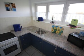Eine Küche mit Herd, Spüle und einem Fenster mit Vorhängen.