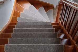 Eine hölzerne Treppe mit Teppichstufen, die nach oben führt.