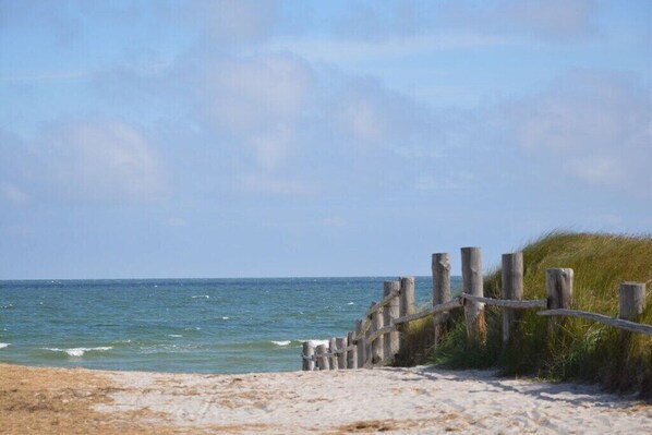 Ein Sandstrand mit einer Holzzaun und Gras.