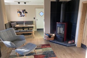 A living room with a sofa, a chair, a fireplace, and a basket with a cat. - Holiday home with 3 bedrooms (Stelle- Wittenwurth)