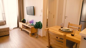 A room with a wooden dining table, chairs, a television mounted on the wall, and a sofa. - Hadi Apart Otel (Bodrum)