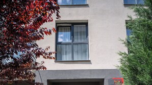 Una entrada de edificio con escaleras, puerta de vidrio y baranda de metal.
