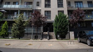 Un edificio de varios pisos con balcones, una sección roja en los pisos superiores y un cielo despejado.