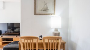 Un comedor con una mesa, dos sillas, una lámpara y un cuadro en la pared.