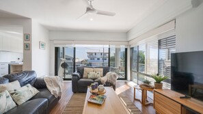 A modern living room with a sofa, coffee table, and television. - Talinga 4 - Lifestyle Yamba (YAMBA)