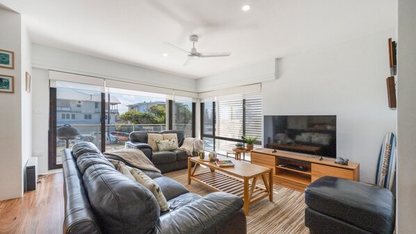 A modern living room with a leather sofa, wooden coffee table, and a flat-screen TV. - Talinga 4 - Lifestyle Yamba (YAMBA)