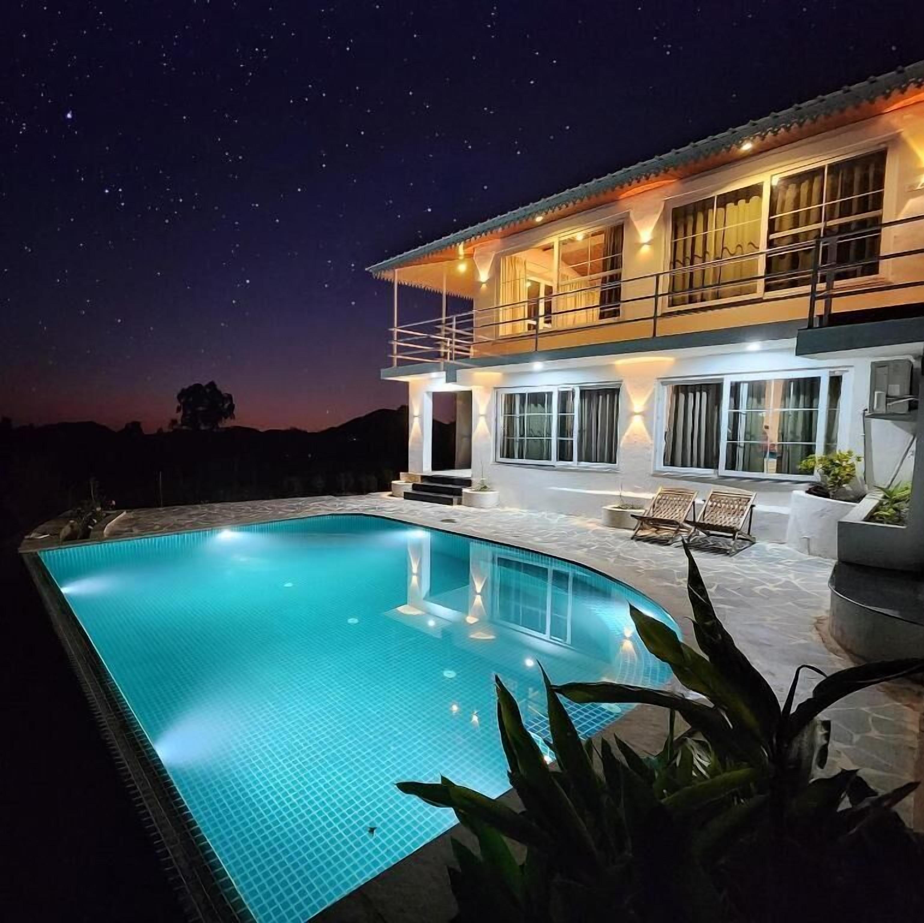 Un hotel moderno con piscina, ampie finestre e un balcone con vista sulla piscina.