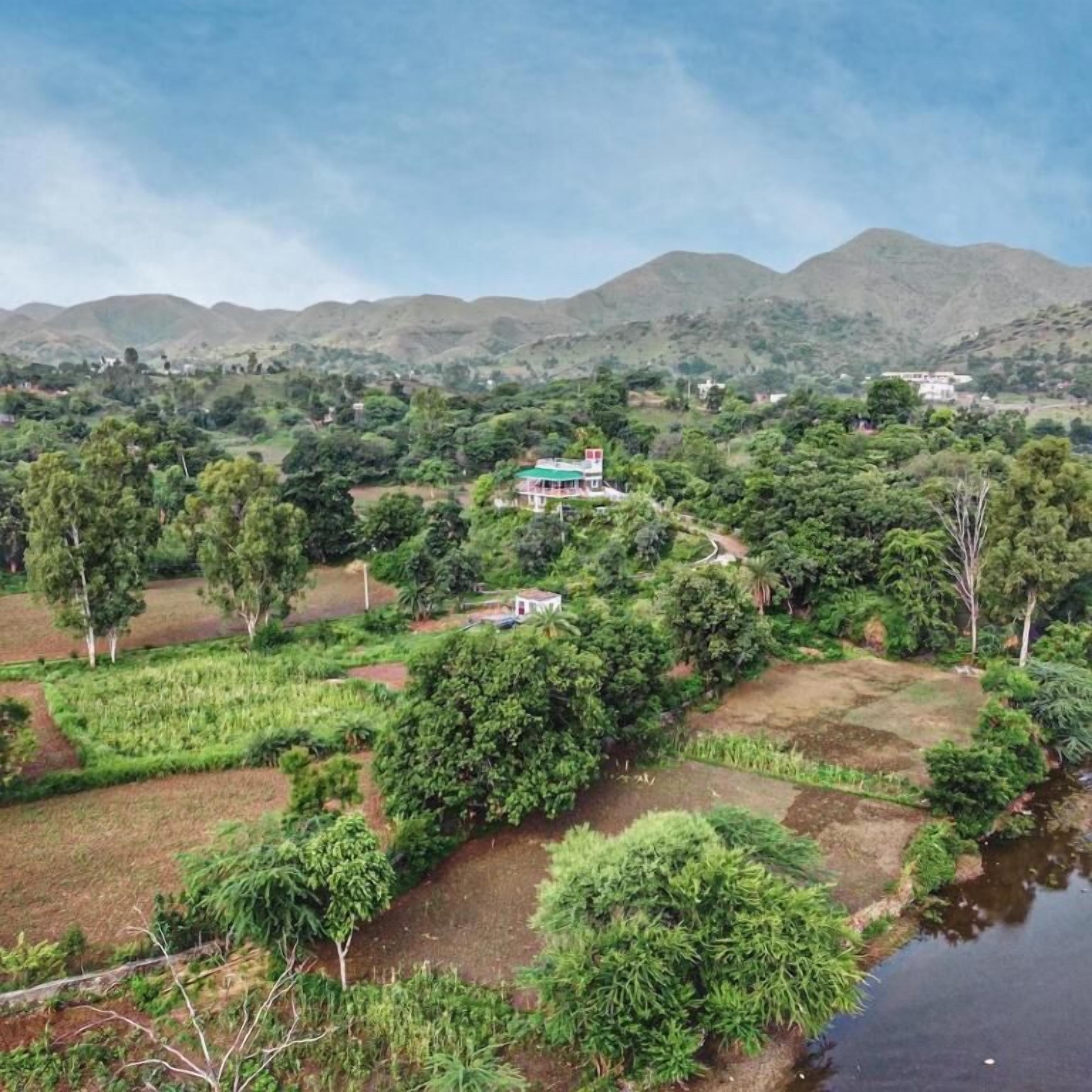 A rural landscape with a house surrounded by fields and a river.