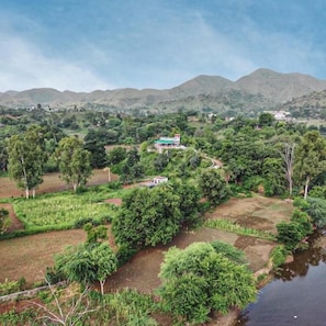A rural landscape with a house surrounded by fields and a river.