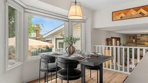 An open-plan dining area with a table set for four, a hanging light fixture, and a view of the outside. - The Evergreen Château - Pool & HotTub - Barrel Sauna - Gym (Edmonton)