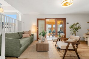 Un soggiorno moderno con un divano verde, un tavolino in legno e due sedie in legno.