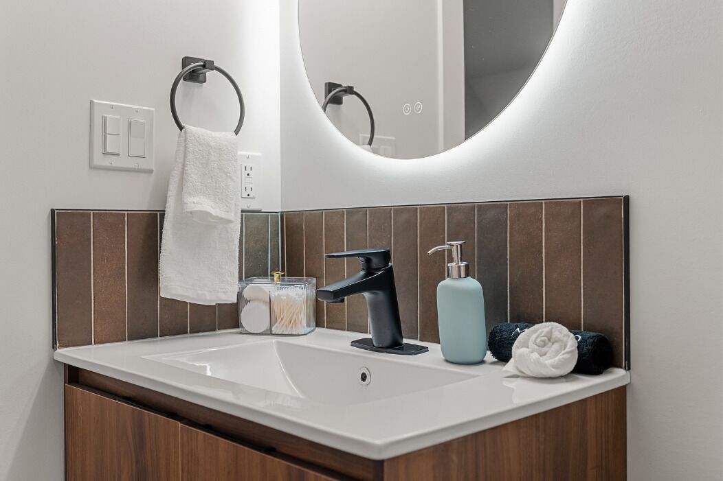Un bagno con lavandino bianco, rubinetto nero e specchio.