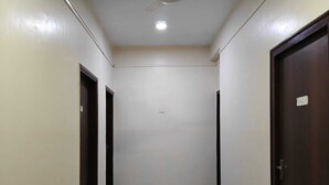 A hallway with a ceiling fan, a light fixture, and two doors on either side. - Amit Hotel (Kolkata)