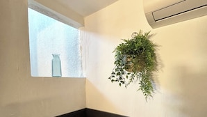 Et badeværelse med et vindue, en hængende plante, et håndklædestativ og et badekar.
