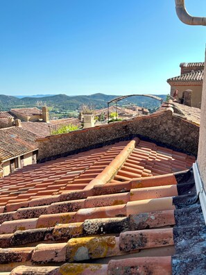 Terracotta-Dachziegel, eine Steinmauer und eine Aussicht auf ferne Hügel.