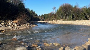 Une rivière aux eaux claires, bordée de rochers et d’arbres.