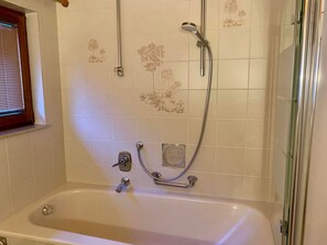 A bathroom with a bathtub, a shower with a handheld showerhead, and a glass shower enclosure.