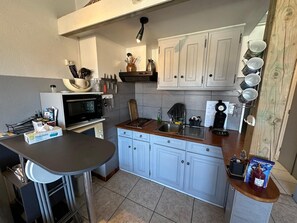 A compact kitchen with a microwave, stove, sink, and cabinets. - T2 Apartment 5 Minutes from the Beach with Wi-Fi and Air Conditioning (Six-Fours-les-Plages)
