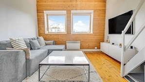 A modern living room with a grey sofa, a coffee table, and a white cabinet. There are two windows with a view of buildings and a wooden ceiling. - 3P duplex on the outskirts of Paris (Le Kremlin-Bicêtre)