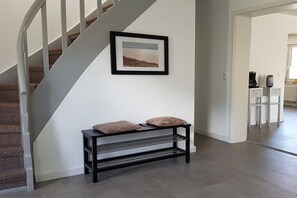Eine Treppe mit weißer Geländer, ein schwarzer Konsolentisch mit zwei Kissen und ein gerahmtes Bild an der Wand.