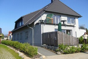Une maison à deux étages avec un balcon, une clôture en bois et une allée pavée.
