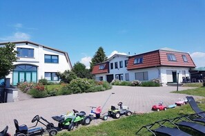 A residential area with two houses, a paved driveway, and various children's toys. - Holiday apartment with 2 bedrooms (Waldeck)