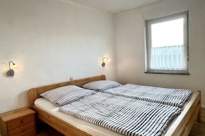 Ein Schlafzimmer mit zwei Betten, einem Nachttisch und einem Fenster mit Vorhang.