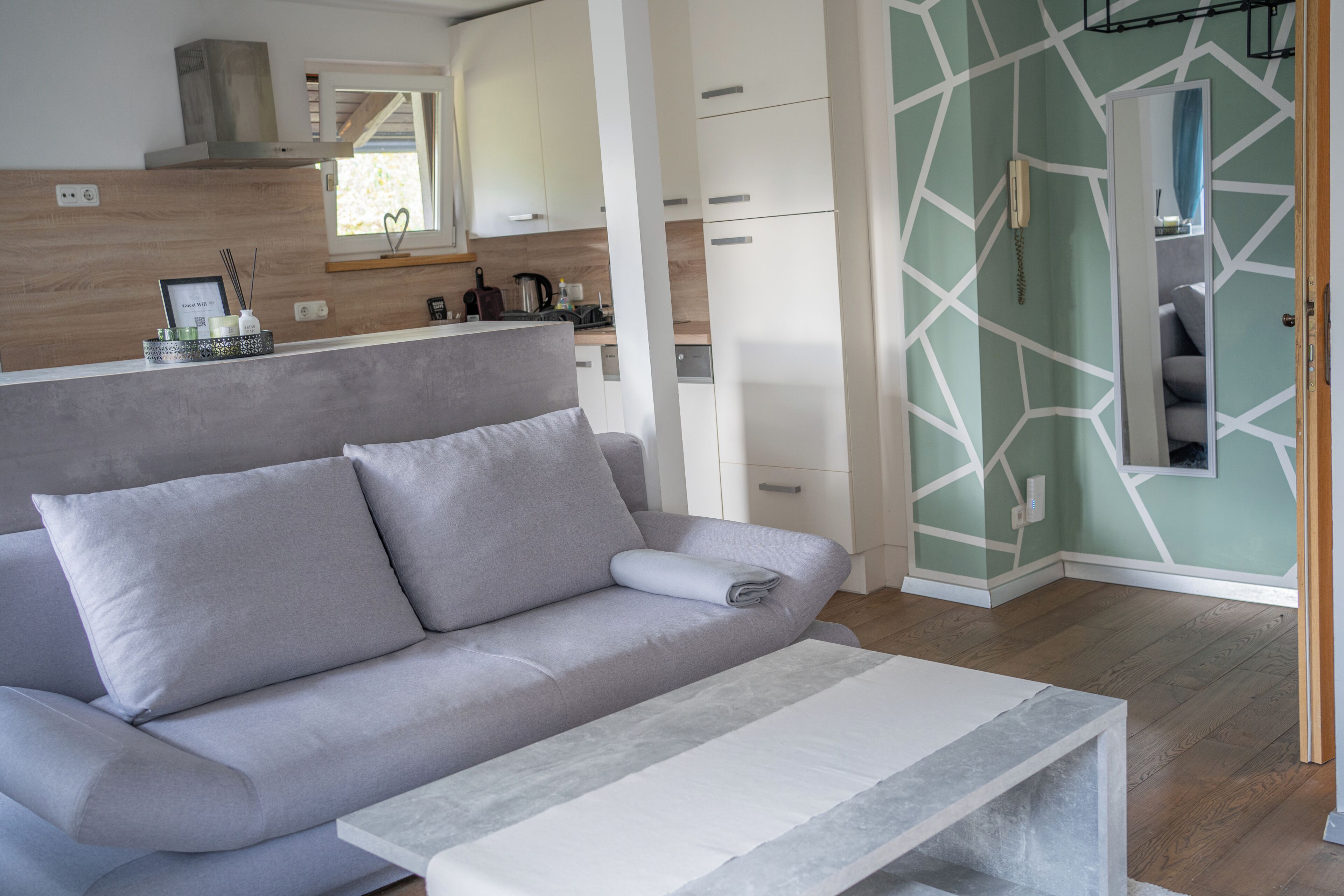 Un espace de vie moderne avec un canapé, une table basse et une cuisine en arrière-plan.